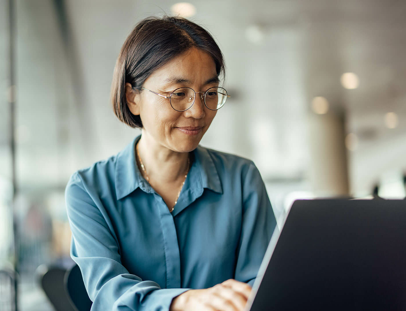Asian woman looking at her laptop blurry background