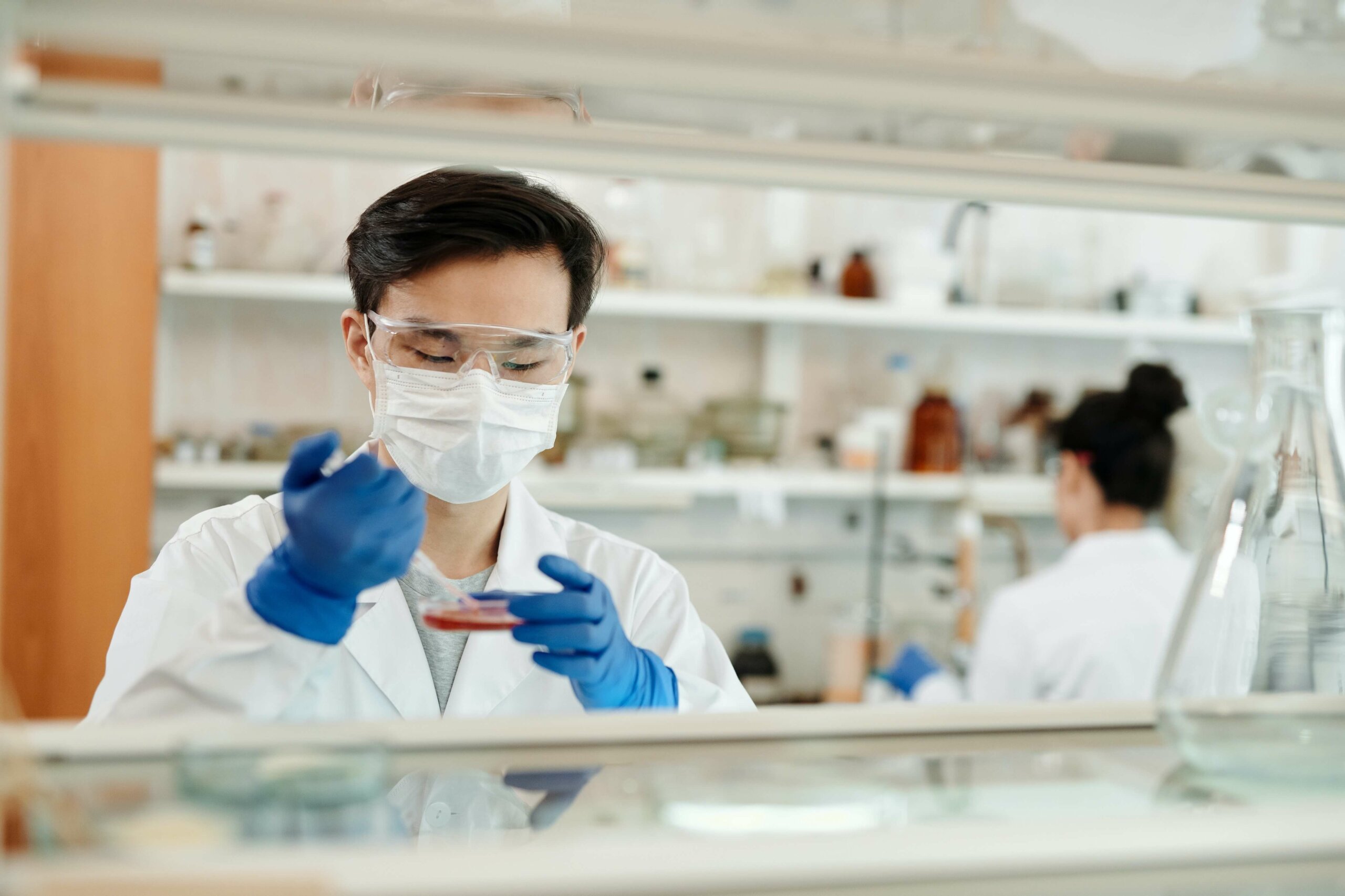 male scientist in white lab coat in a laboratory working with petri dish